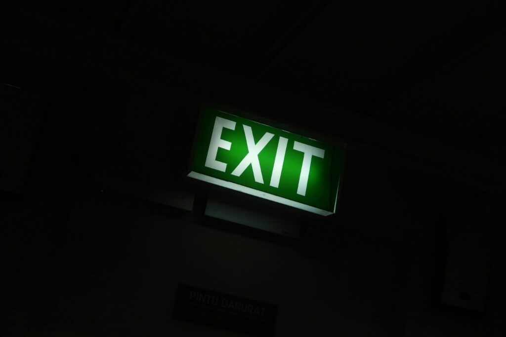 A glowing green exit sign provides guidance in a dimly lit indoor space.